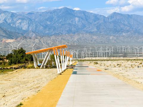 A bike path in Palm Springs with wind turbines and mountain views beyond